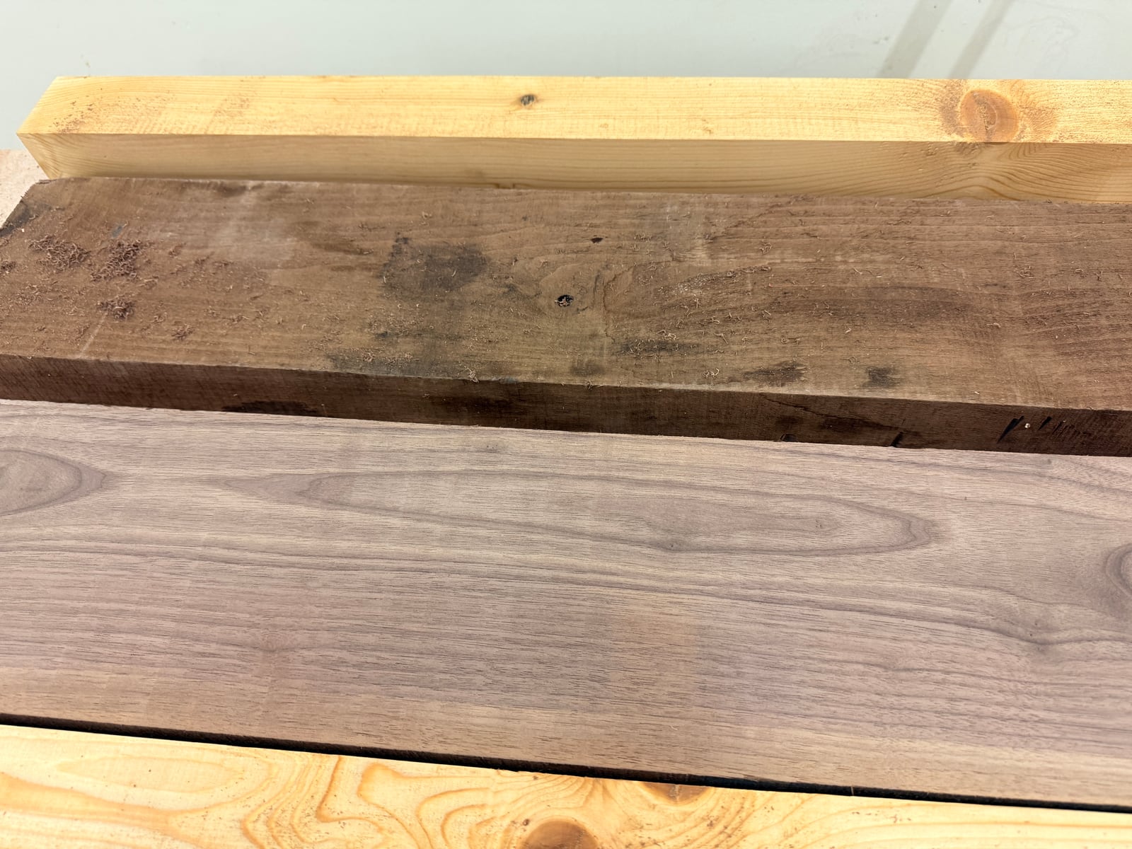 Two rough walnut boards, one with a freshly surfaced face showing clean grain