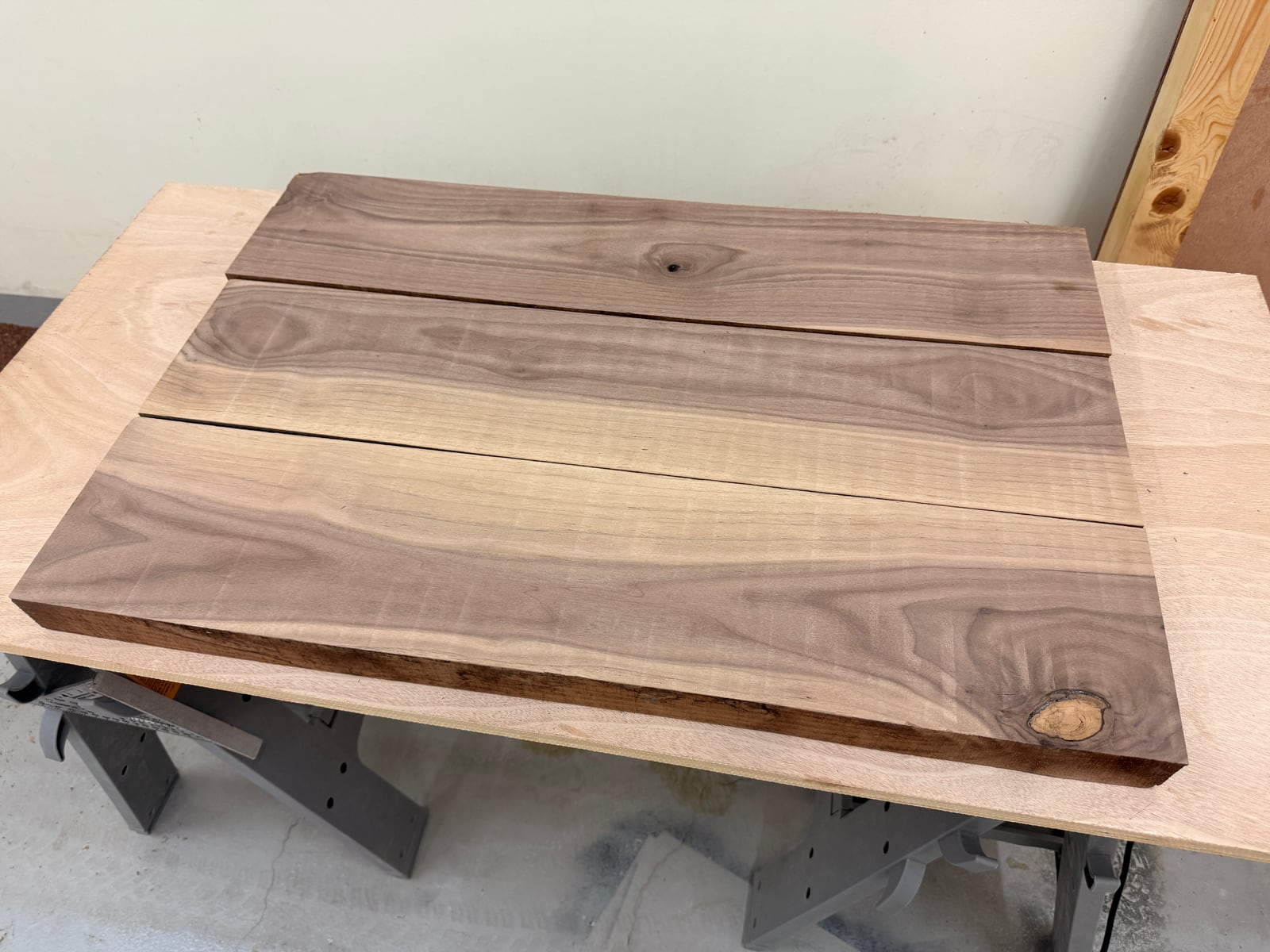 Three surfaced walnut boards side by side, with a round knot near one corner
