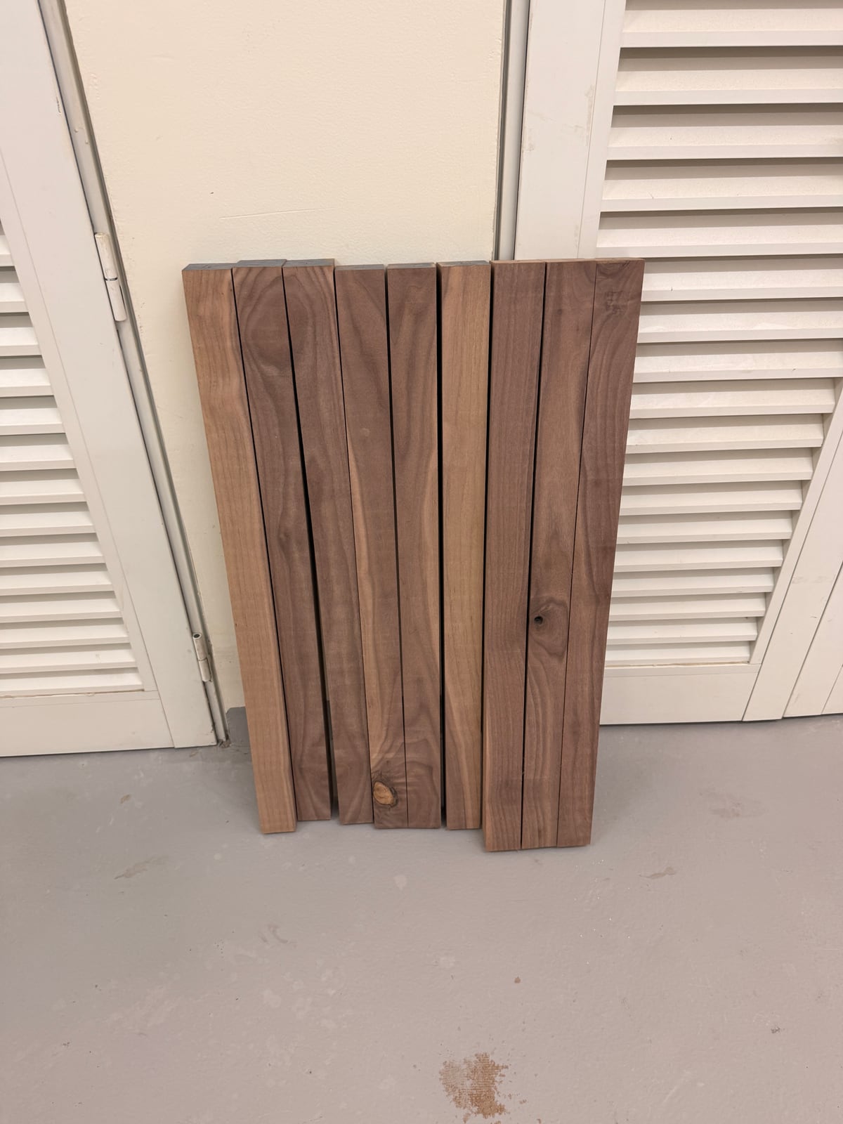Nine walnut strips standing on end against a wall