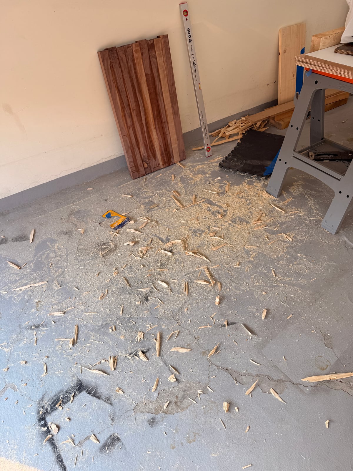 A garage floor covered in wood chips beside a sawhorse