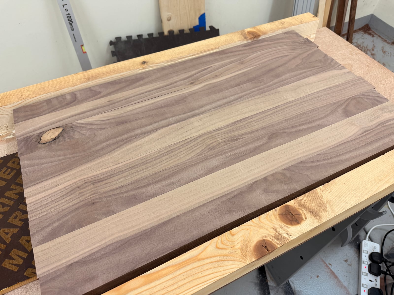 The glued-up walnut panel surfaced flat on the sled, with the knot near one edge