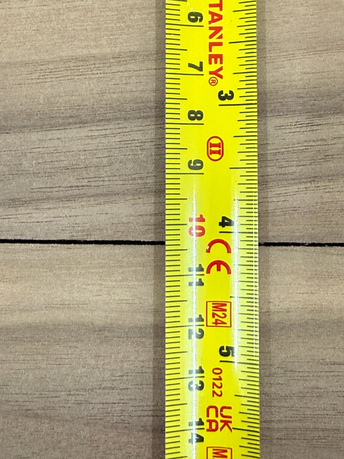 A tape measure held beside a dark gap in a glue joint