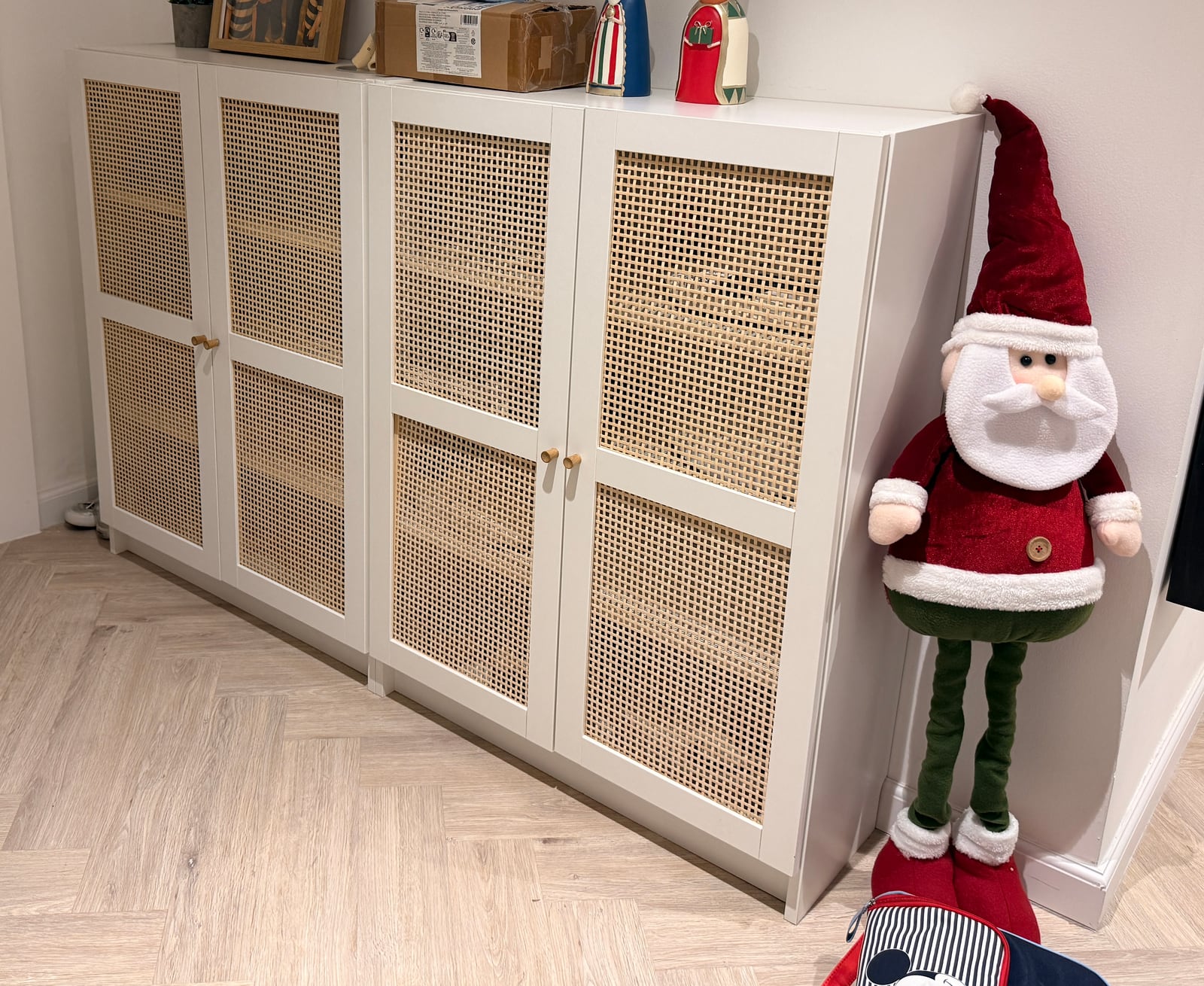 Two white IKEA bookcases with cane doors against a living room wall, a Santa figure leaning beside them