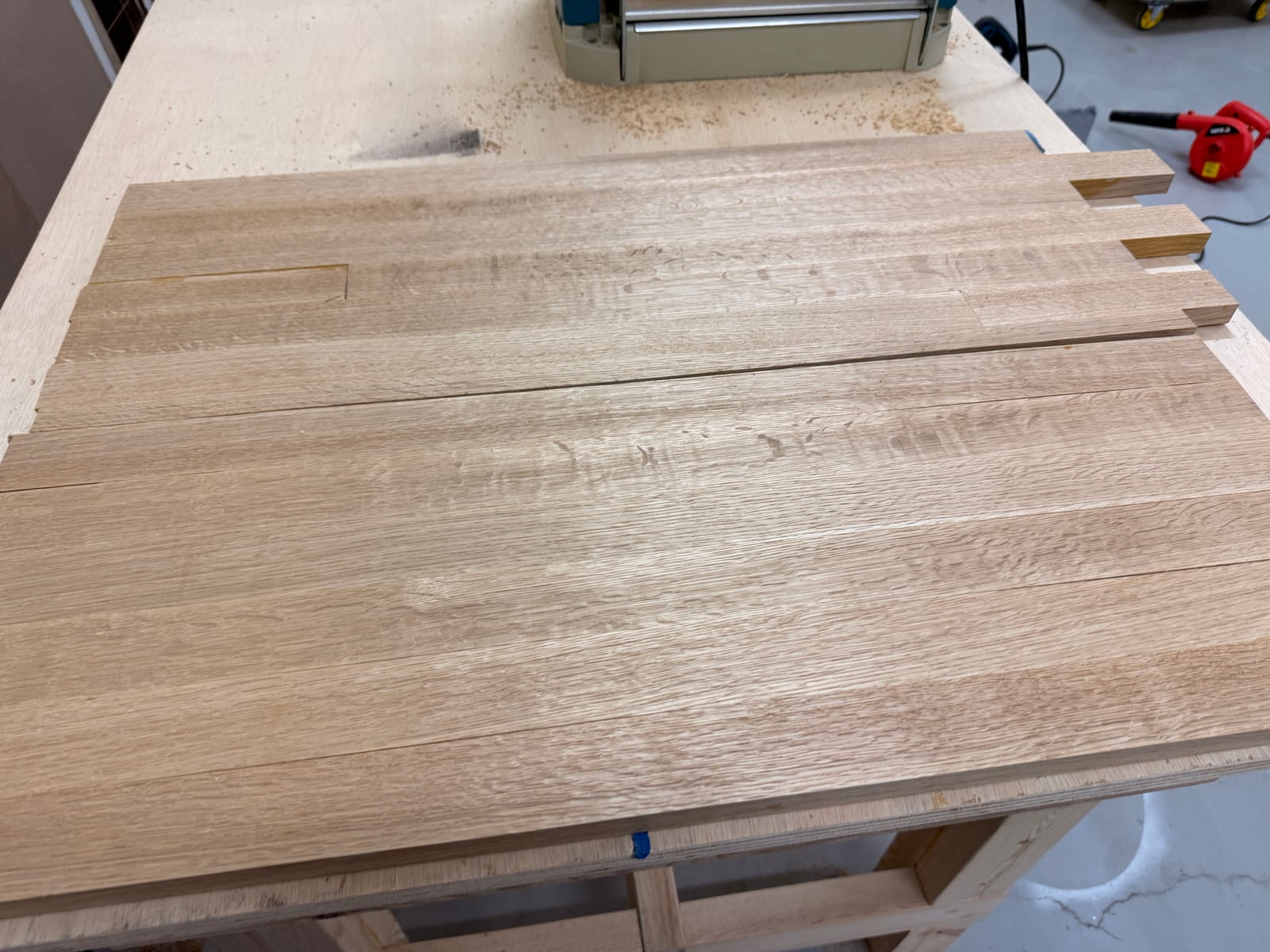 White oak boards surfaced and ripped into strips, laid out on the workbench