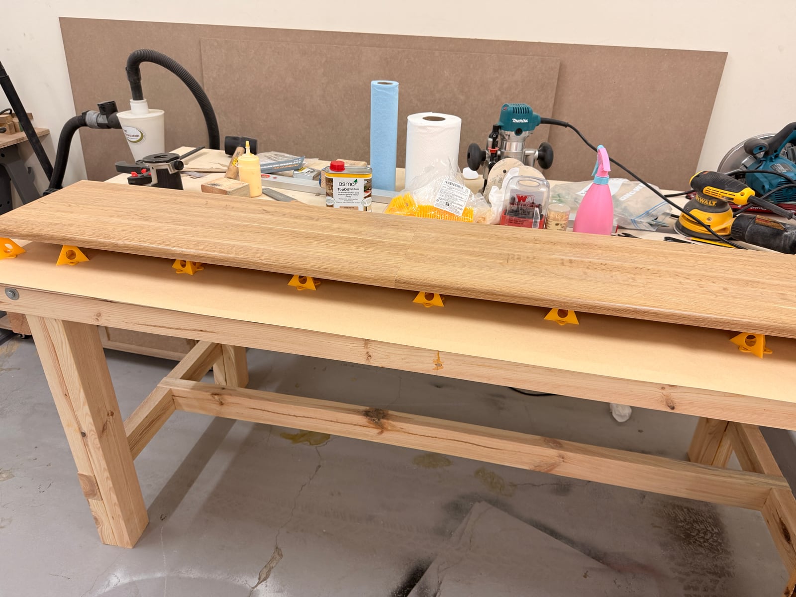 The oak panel on the workbench after oiling, the grain darkened and the surface sheening