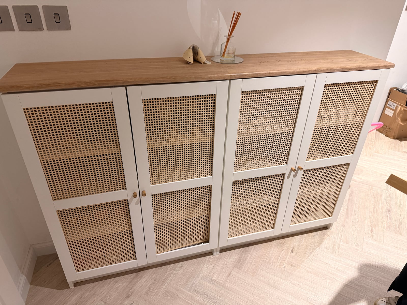 Two white IKEA bookcases with cane doors, topped with a single oiled white oak panel