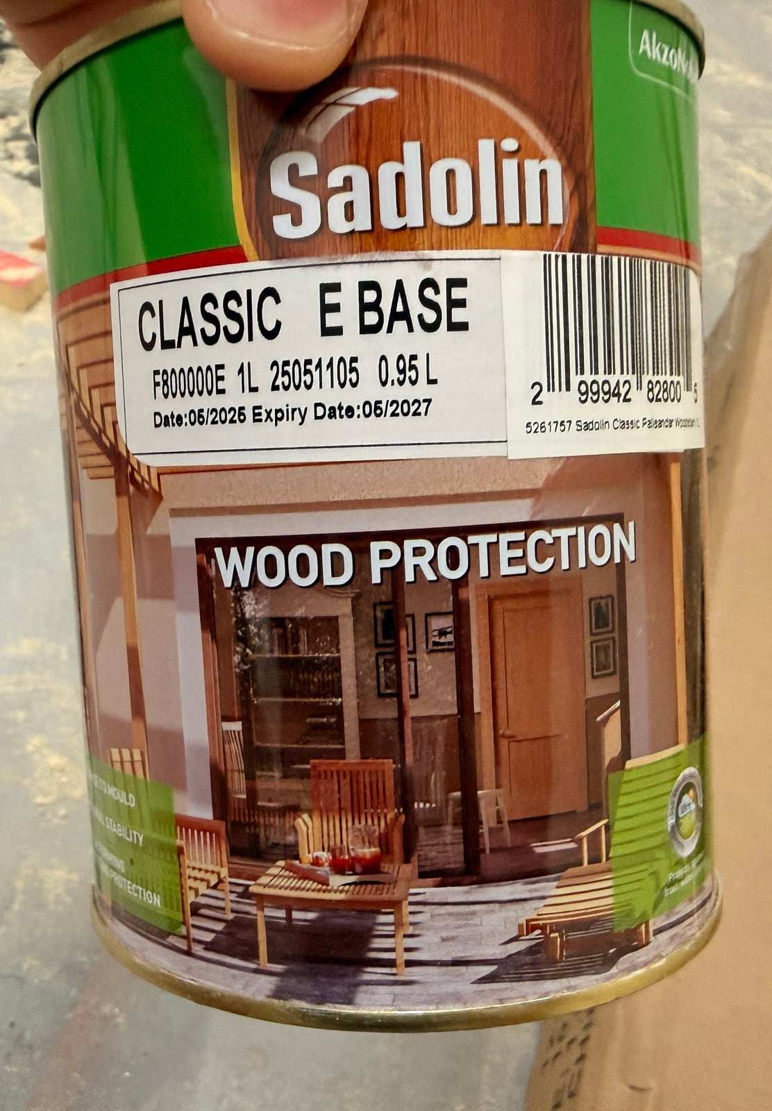 A tin of Sadolin Classic wood stain held up in the garage