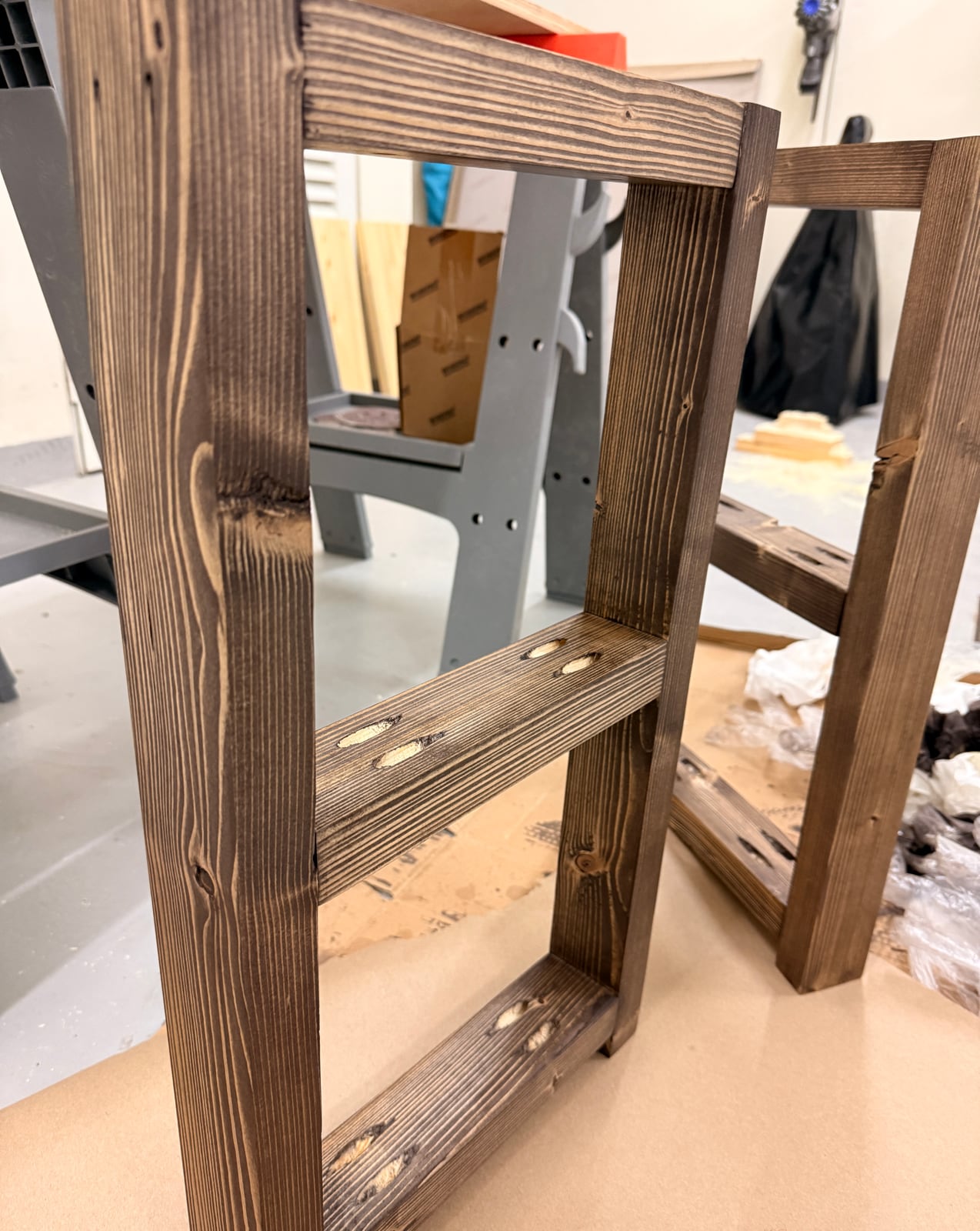 The stained dark-brown base of the table on brown paper, pocket holes showing on the rails