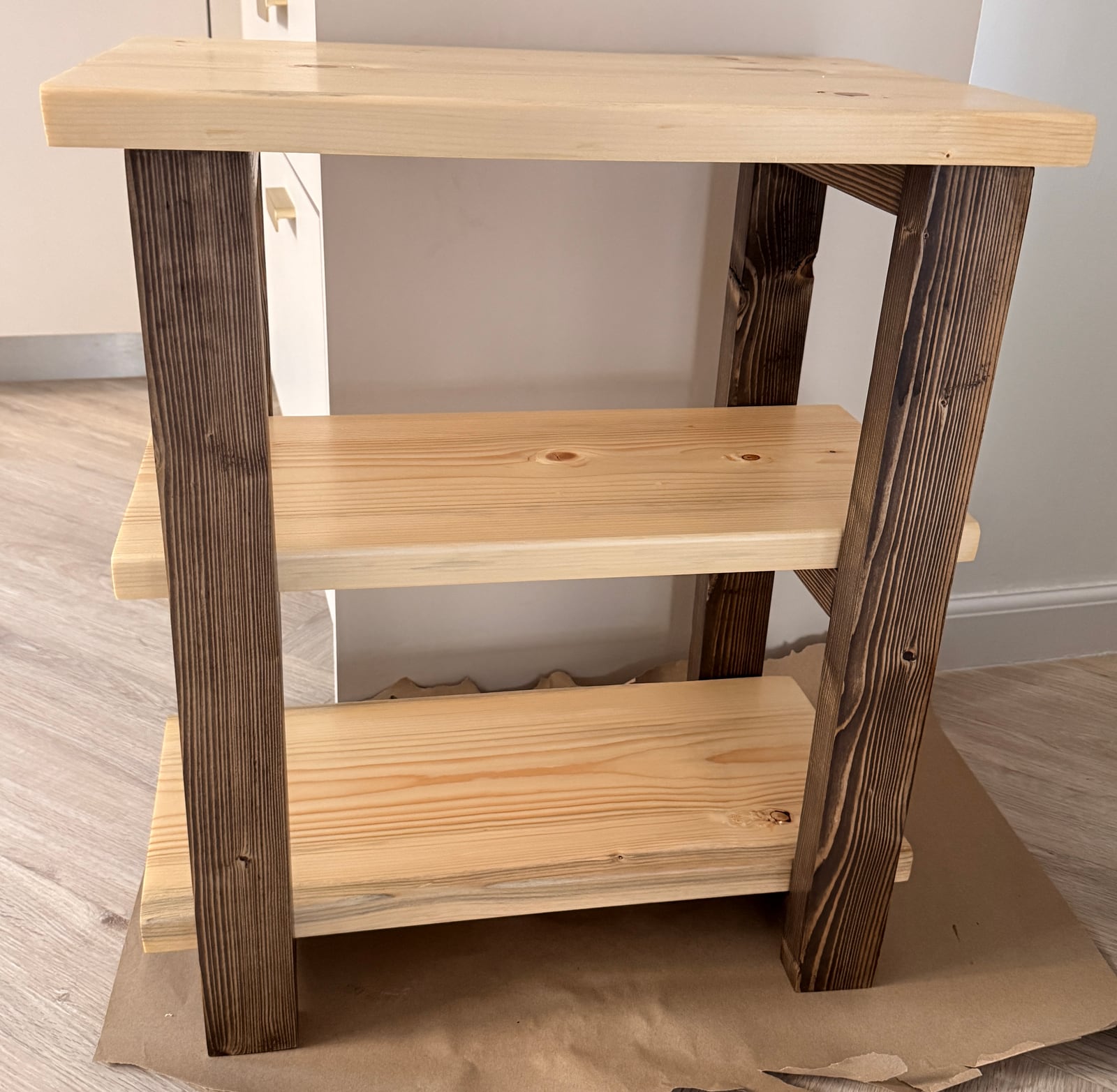 The table on brown paper: the stained base against the unstained natural shelves