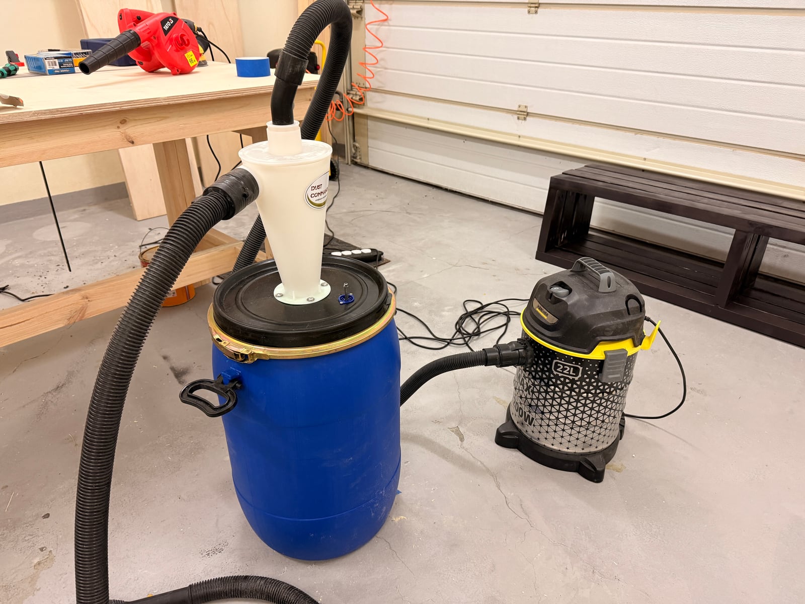 A blue plastic barrel set up as a dust collection container with a cyclone on its lid