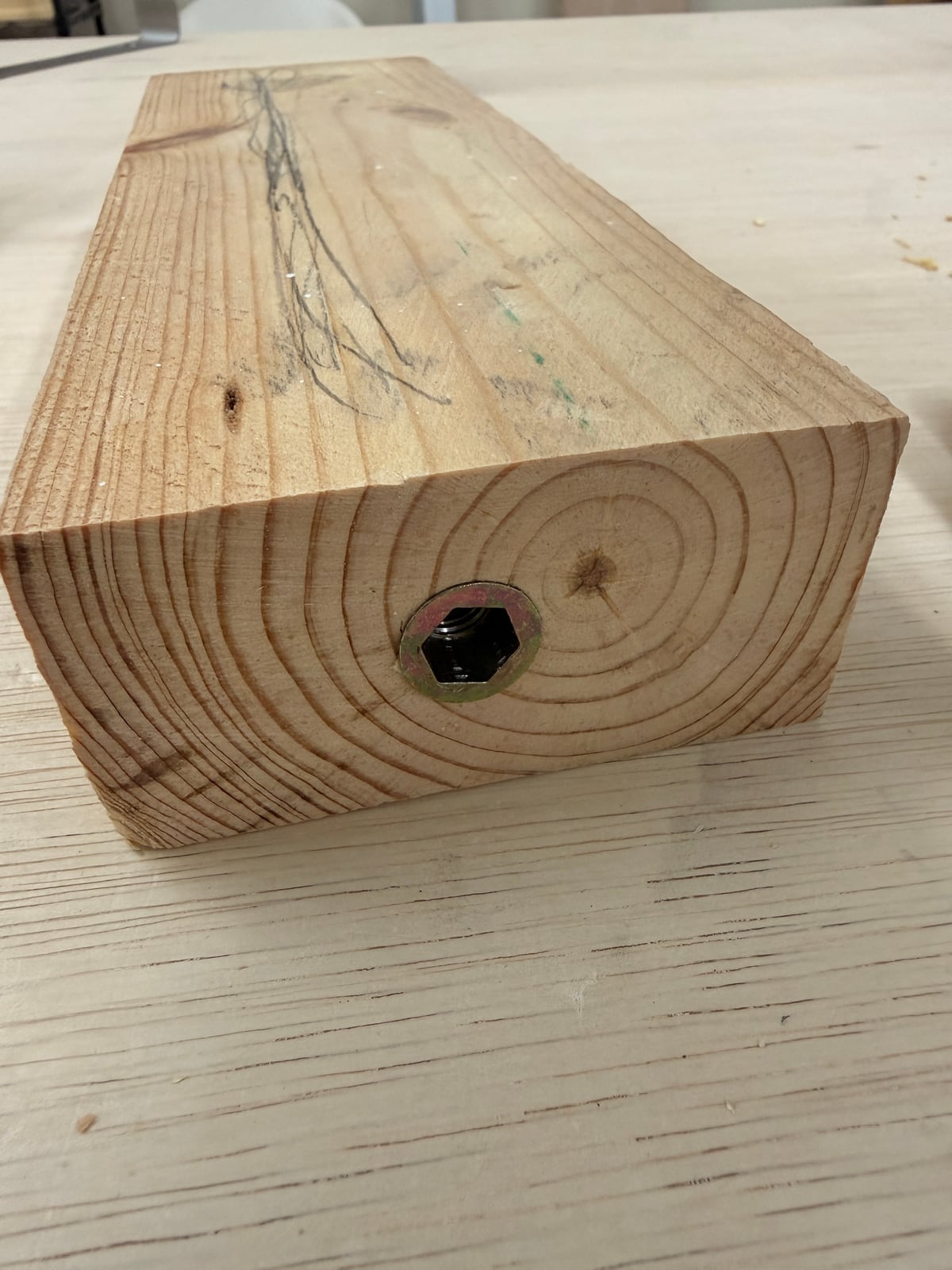 The end of a 2x4 leg with a brass threaded insert sunk into it