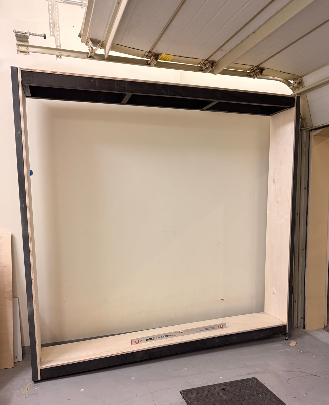The empty shelf frame standing against the garage wall, level and square