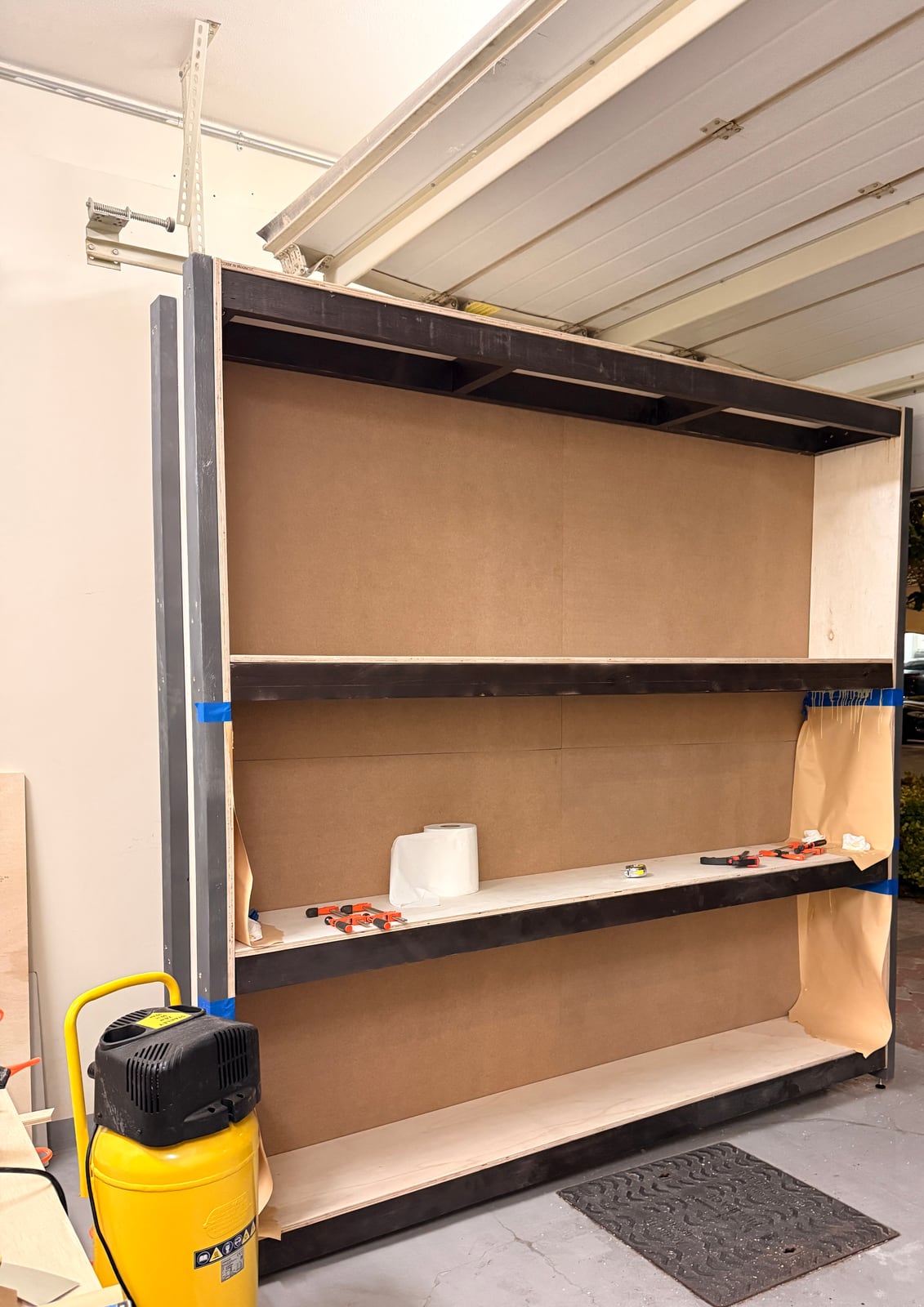 The shelf unit with its boards fitted, standing against the garage wall