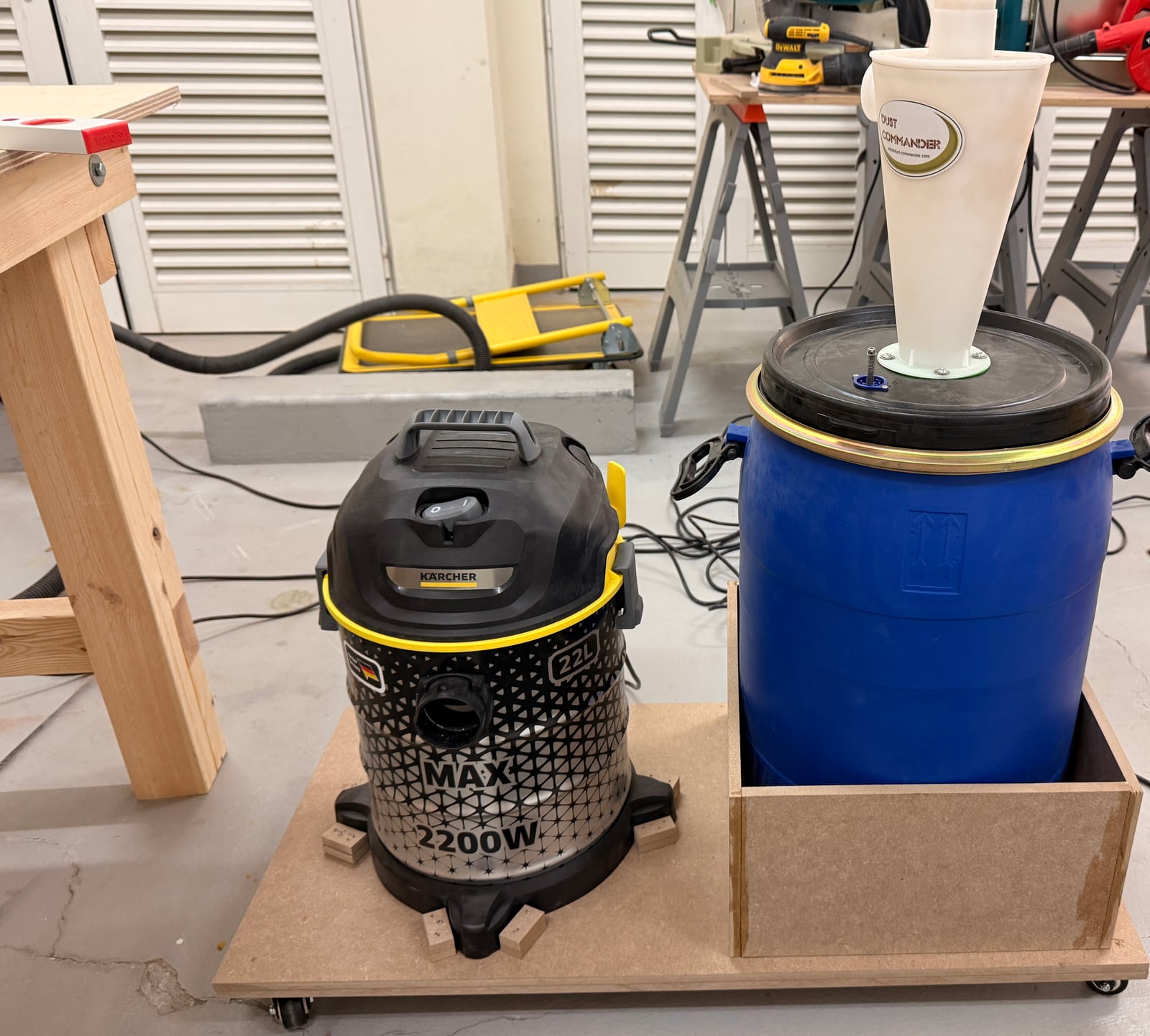 The shop vac and cyclone-topped blue barrel sitting together on a wheeled MDF cart
