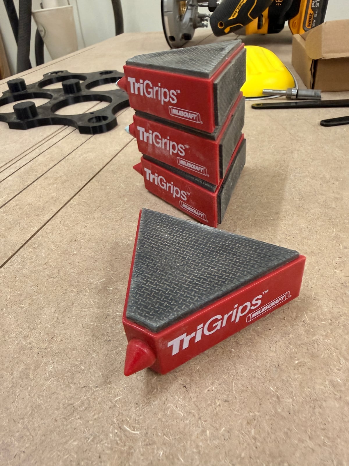 Triangular work grippers with a rubberised top face and matching base, stacked and in use.