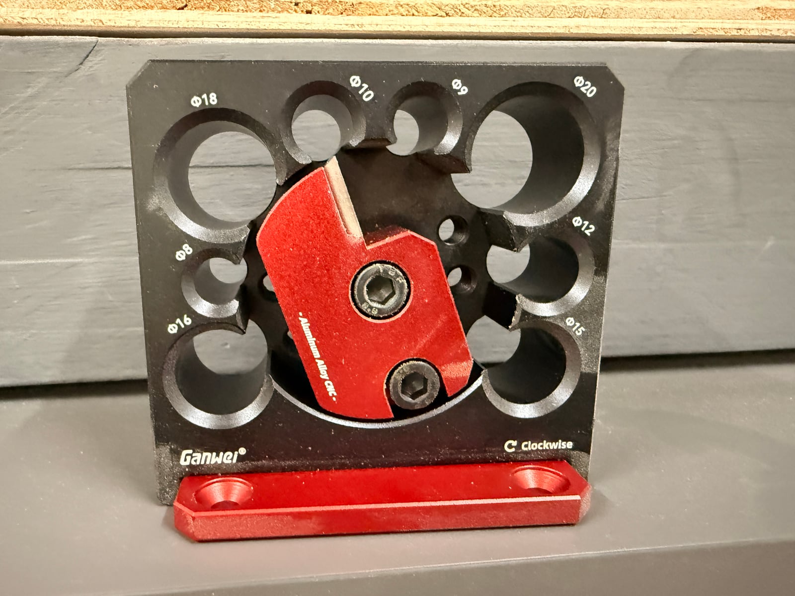 A dowel maker plate, 8mm to 20mm. Each hole has a relieved pocket to clear shavings, and the red block holds the adjustable cutting blade.