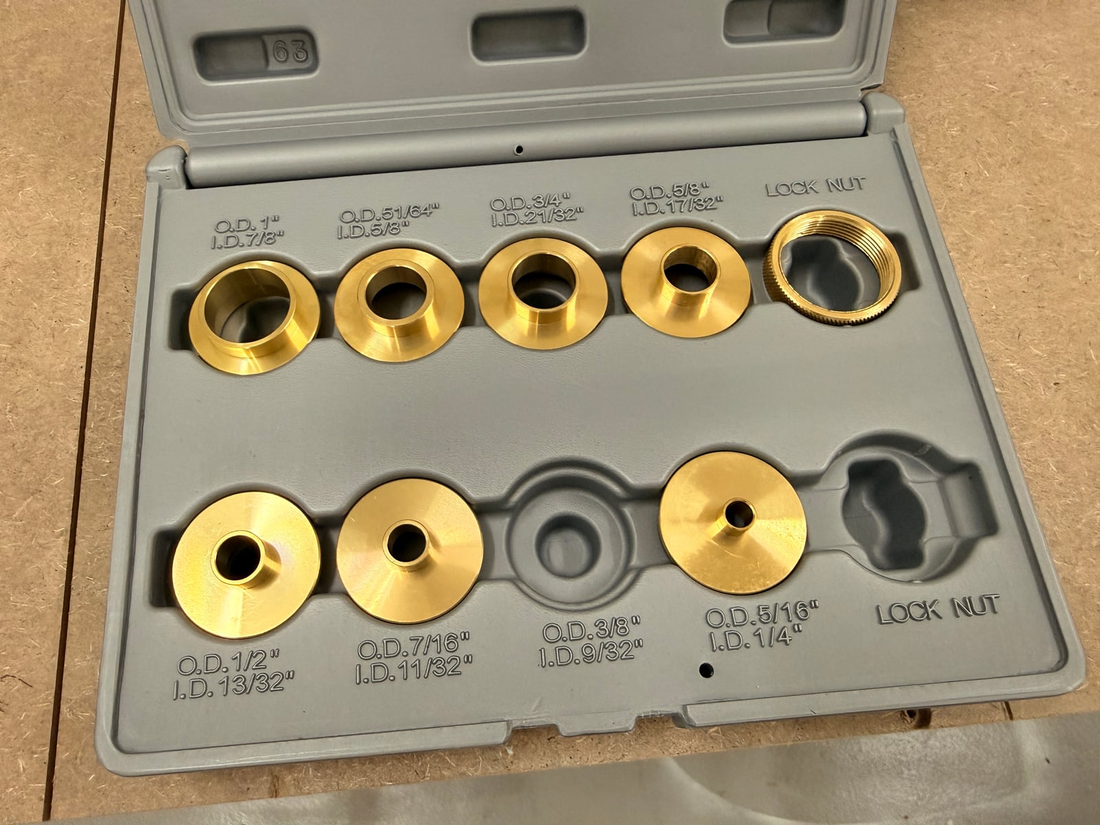 A brass template guide bushing set with lock nuts, each marked with its outside and inside diameter.