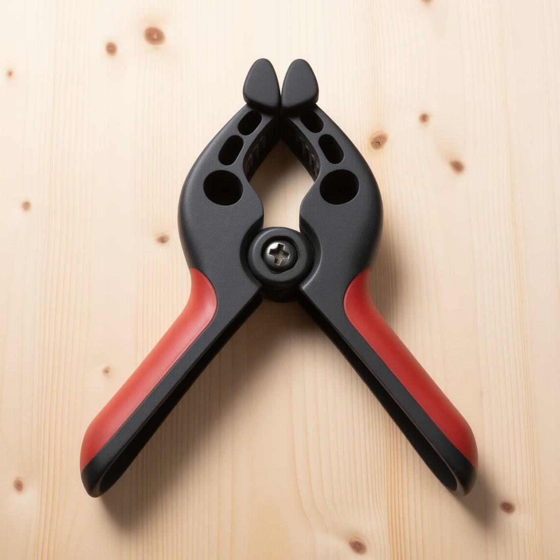 A spring clamp. The torsion spring lives inside the pivot boss -- squeeze the handles, the jaws open, let go and they snap shut with whatever force the spring has.