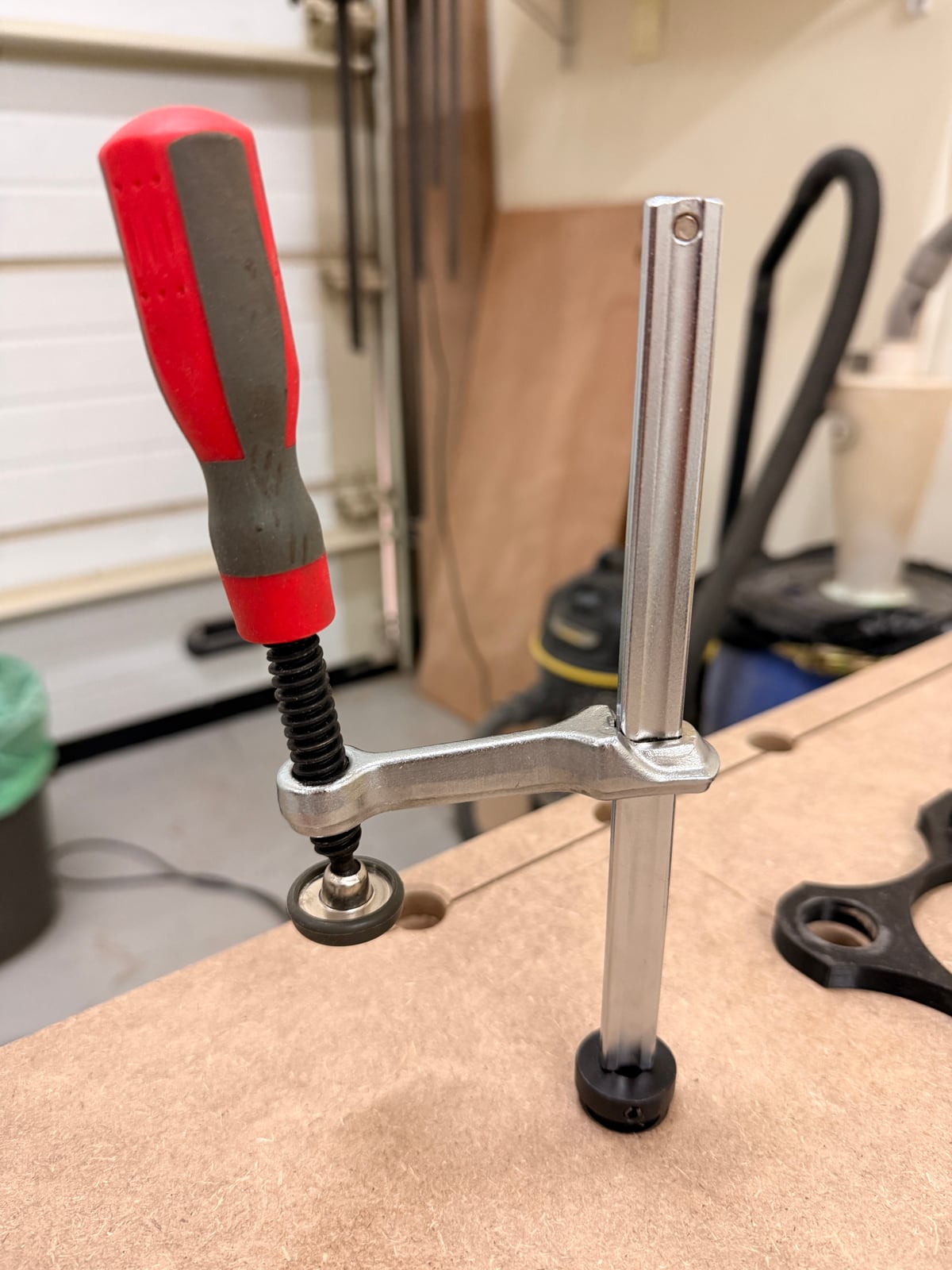 A screw-type hold-down seated in a bench dog hole, clamping down onto the benchtop.