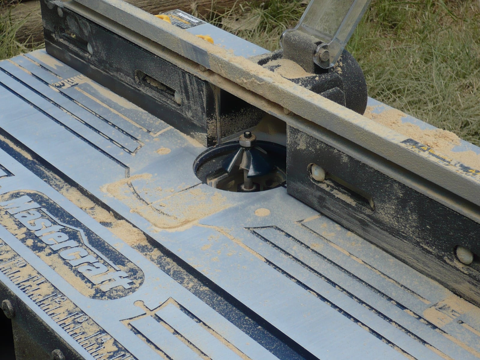 A router table: the router hangs upside down under the top with the bit projecting through, and the stock is fed against a fence.