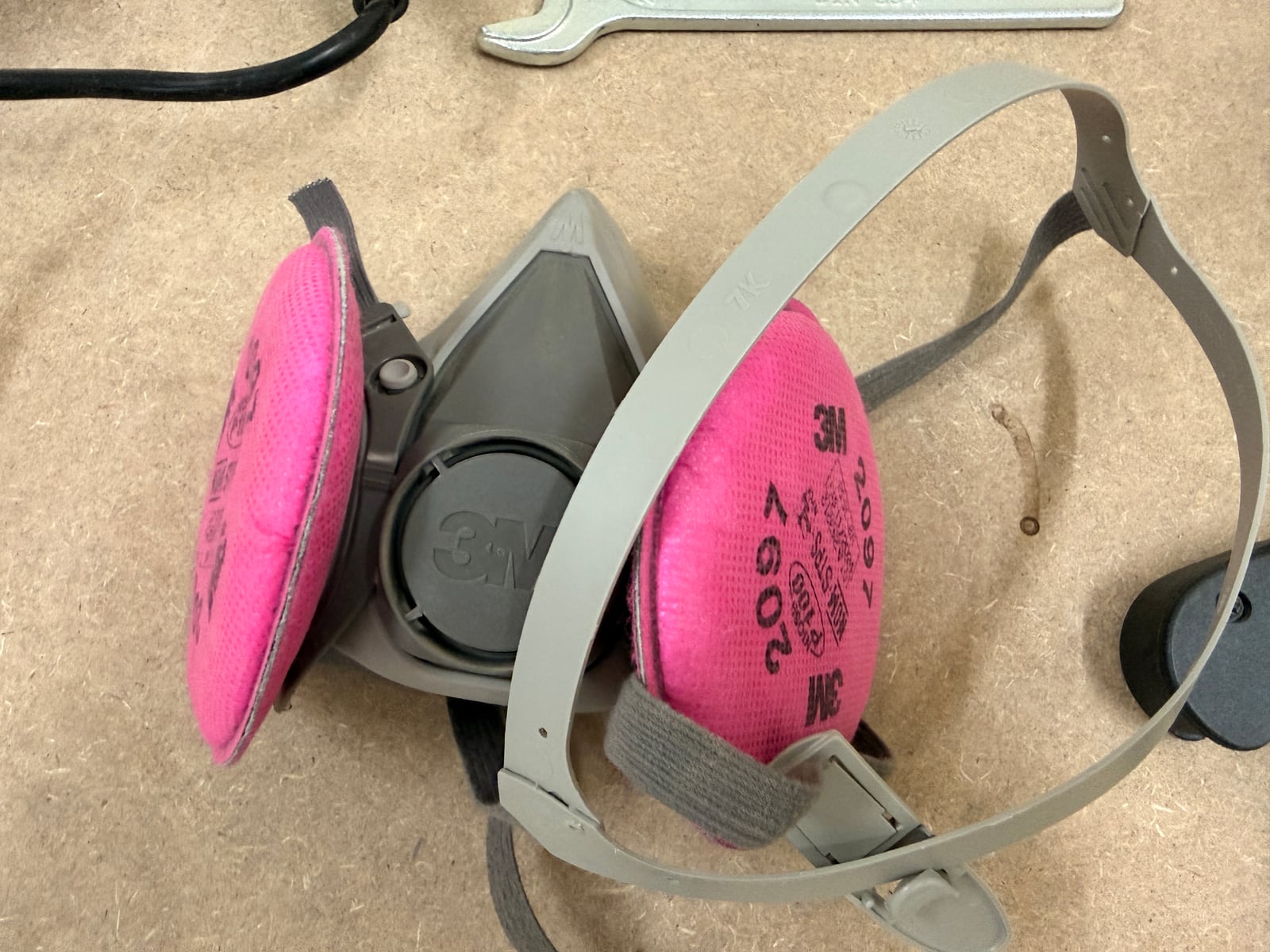 A 3M half-mask respirator fitted with P100 particulate filters -- the pink cartridges. This is the level of protection fine wood dust actually calls for; a paper dust mask is not equivalent.