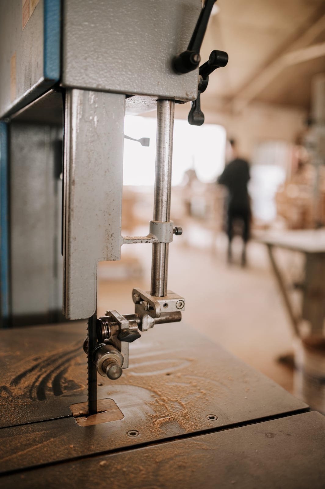 A band saw's blade guide and tensioning mechanism, mid-cut