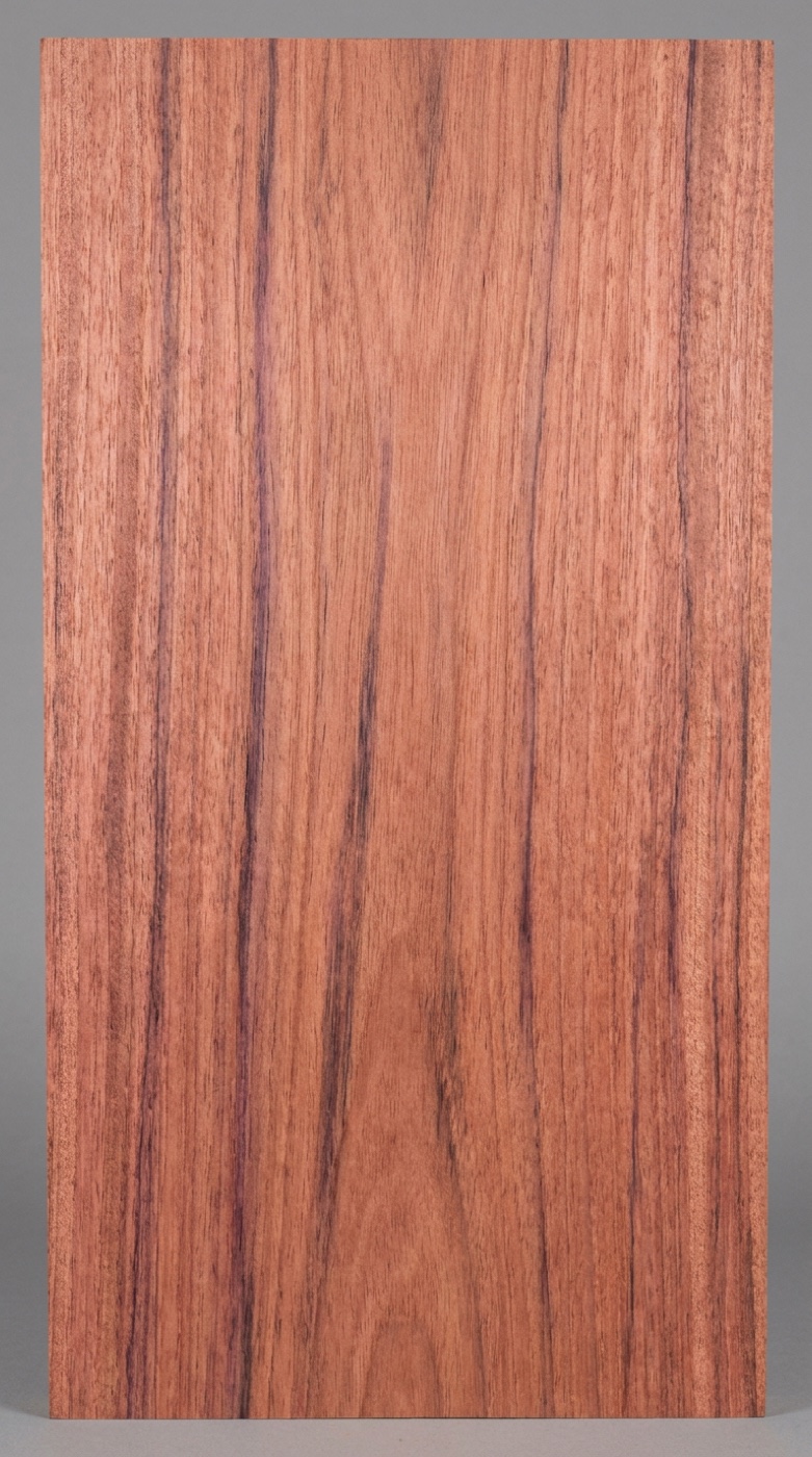 A board of plain-grain bubinga -- pinkish red with darker streaking; the figured grades look nothing like this