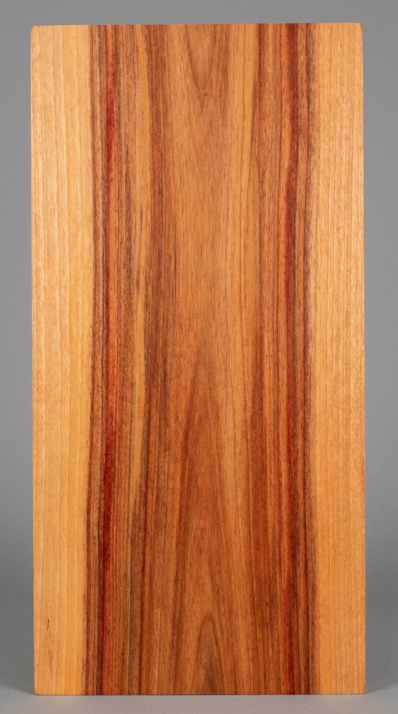 A board of canarywood -- yellow-orange shifting to reddish brown across the same board, with darker streaks